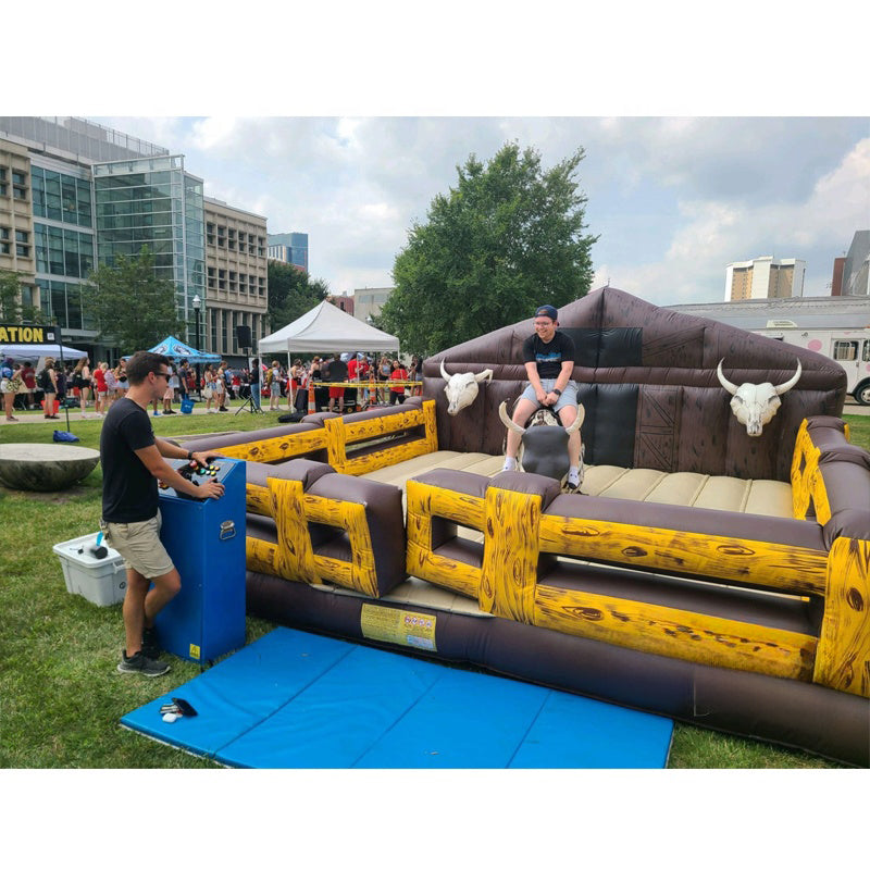 Inflatable mechanical bull riding game with a bull and rider figure, made of commercial grade PVC, requiring a blower for operation.