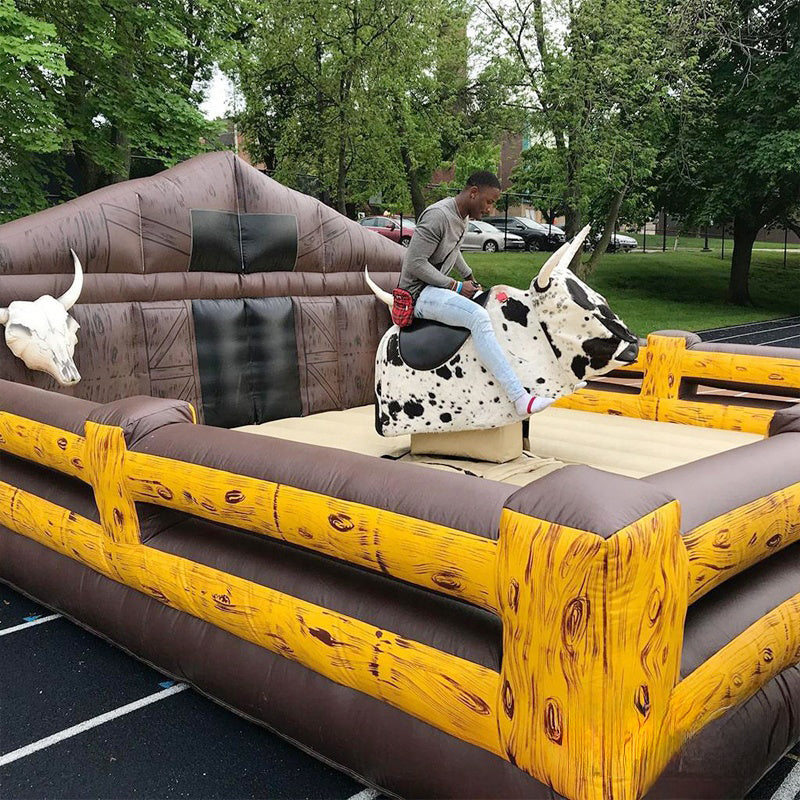 Inflatable mechanical bull riding game with a bull and rider figure, made of commercial grade PVC, requiring a blower for operation.